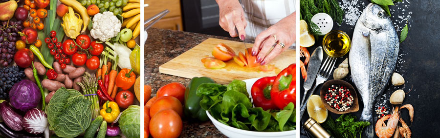 A person cutting tomatoes on a board near vegetables.