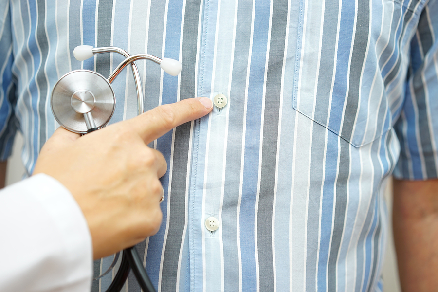 A doctor points to the button on his shirt.